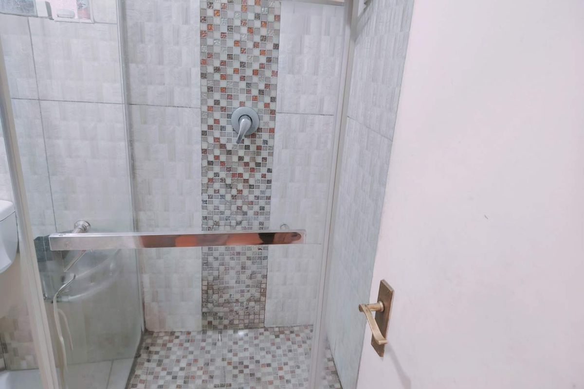 A modern bathroom shower area featuring a glass enclosure and decorative mosaic tile accents on the wall and floor.