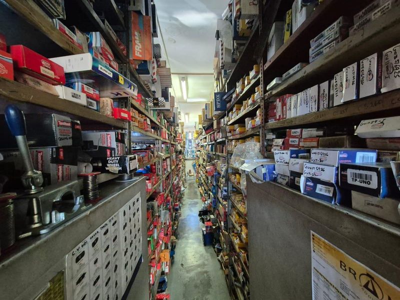 A narrow utility or storage space featuring extensive floor-to-ceiling metal shelving units, currently utilized for organized inventory storage.