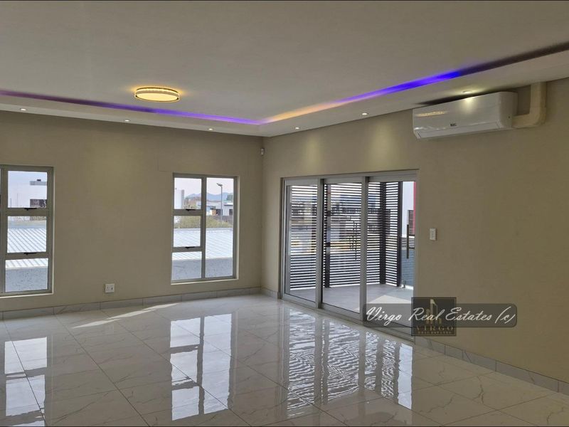 Spacious, modern living area featuring polished tiled floors, recessed ceiling lighting with LED accents, and sliding glass doors leading to an outdoor space.