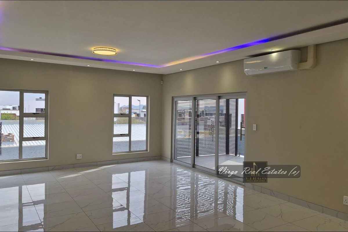Spacious, modern living area featuring polished tiled floors, recessed ceiling lighting with LED accents, and sliding glass doors leading to an outdoor space.