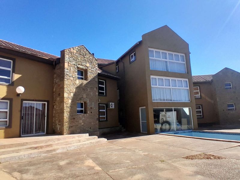 Rear exterior view of a multi-story house featuring a swimming pool, paved patio area, stone facade accents, and large windows.