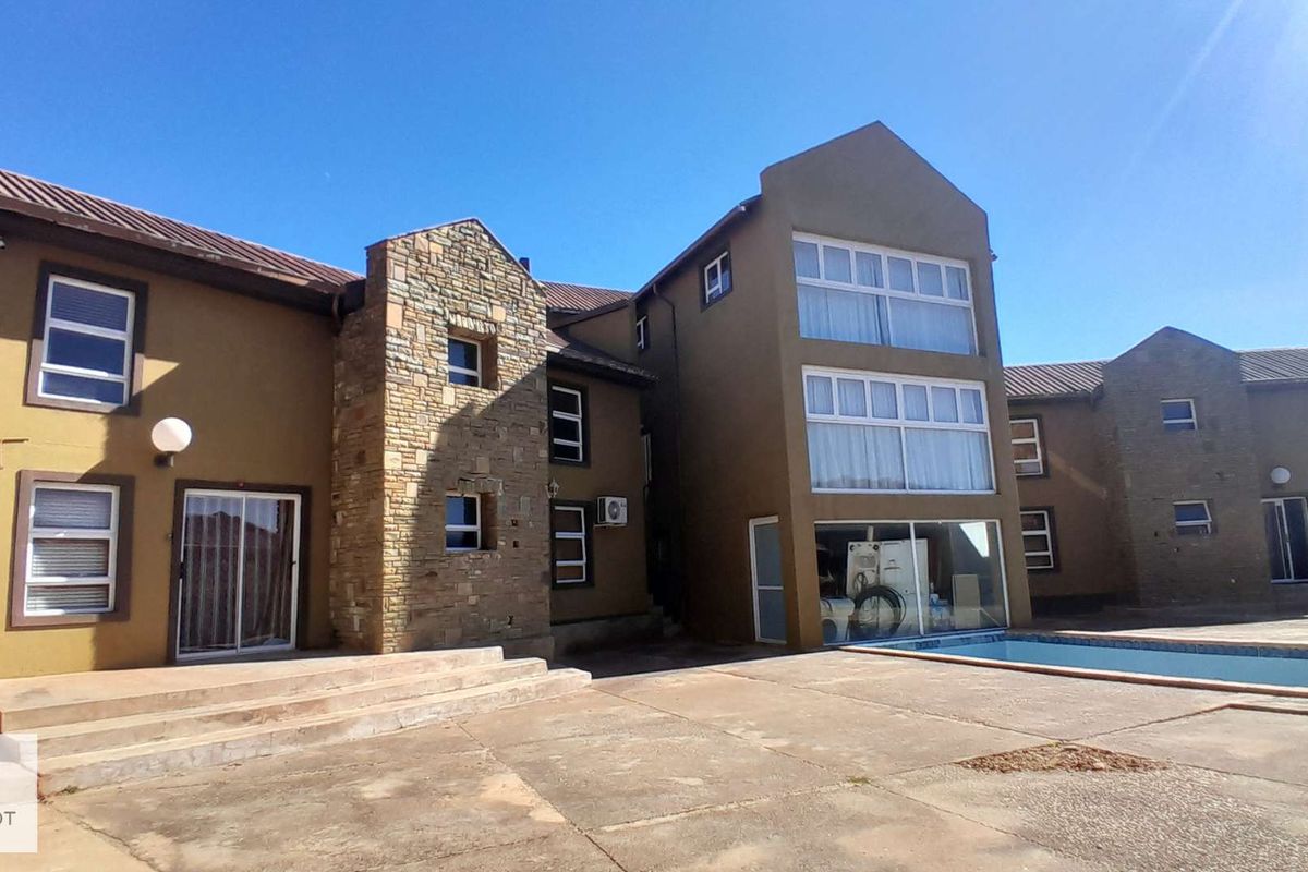 Rear exterior view of a multi-story house featuring a swimming pool, paved patio area, stone facade accents, and large windows.