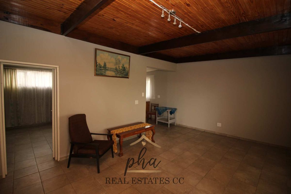 Spacious living area featuring exposed timber beam ceilings, tiled flooring, and neutral wall tones, offering a versatile layout for comfortable family living.