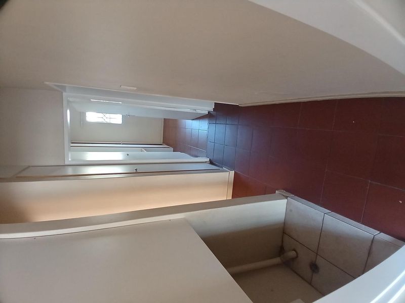 A vacant hallway featuring built-in storage cupboards and tiled flooring, providing access to other areas of the apartment.