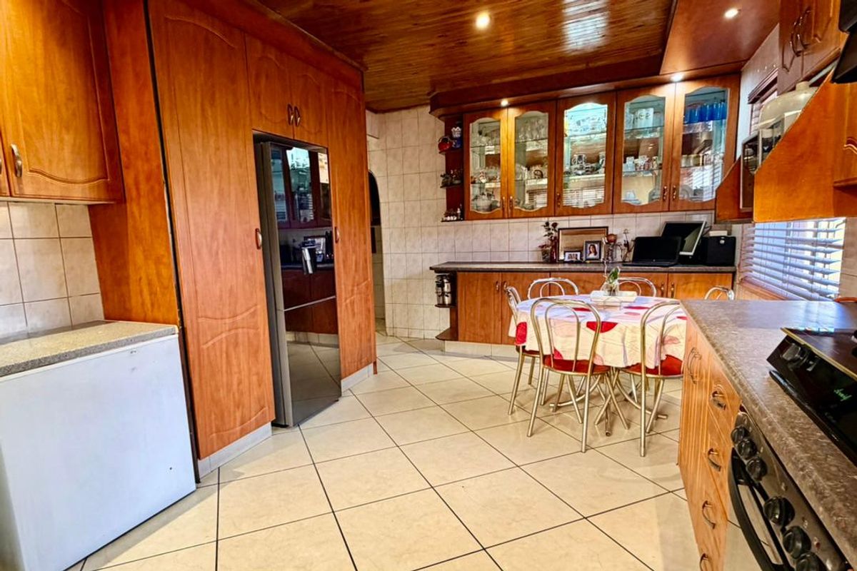 Spacious kitchen featuring extensive built-in wooden cabinetry, tiled flooring, timber ceiling, and integrated oven, offering a functional layout with ample storage and display space.