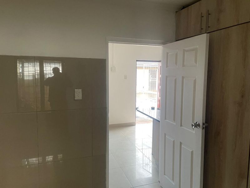 A functional hallway area featuring tiled flooring, built-in cabinetry, and a tiled wall section, providing access to adjacent living spaces.