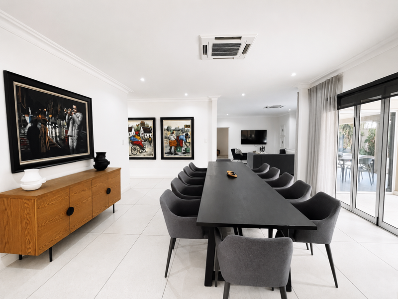 Spacious dining area featuring modern tiled flooring, recessed ceiling lighting, ducted air conditioning, and large sliding glass doors leading to the outdoor patio.