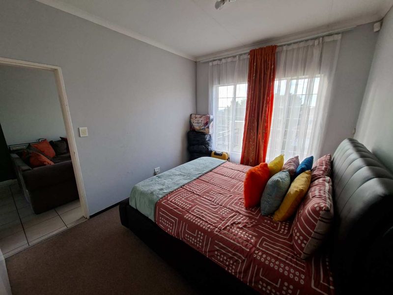 A bedroom featuring carpeted flooring and a sliding door leading to an outdoor area, with neutral wall finishes.