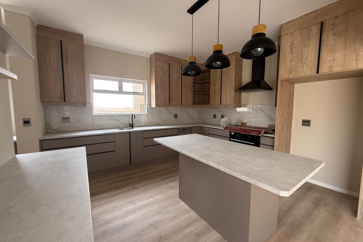 Modern kitchen featuring wood-look cabinetry, stone-effect countertops, a central island, and integrated lighting, offering a clean and contemporary culinary space.
