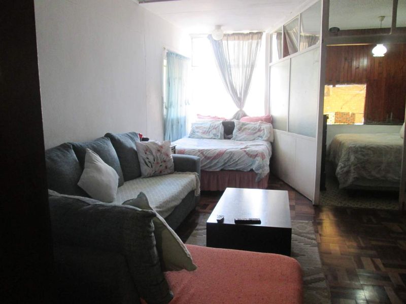 Open plan living area featuring parquet flooring and a glass-paneled partition wall separating the sleeping quarters.
