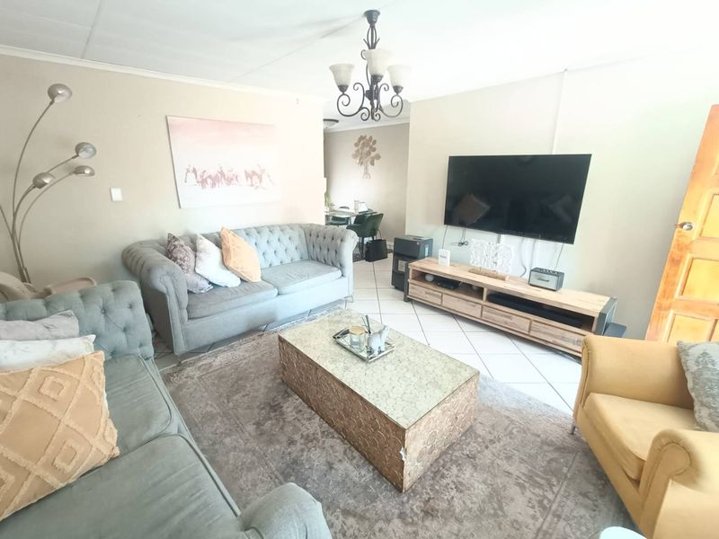 A comfortable living room featuring ceramic floor tiles and a central chandelier, providing a functional space for relaxation and entertainment.