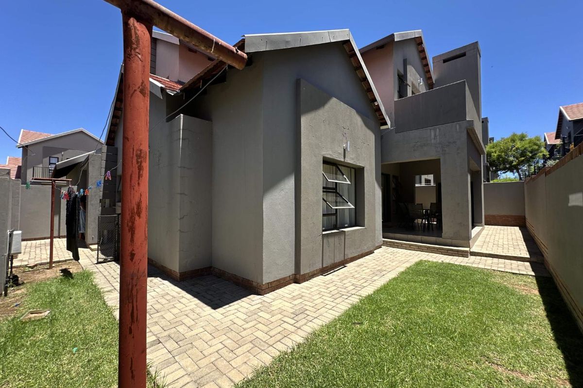 Rear view of the property featuring a paved walkway, small lawn area, and a covered patio space.