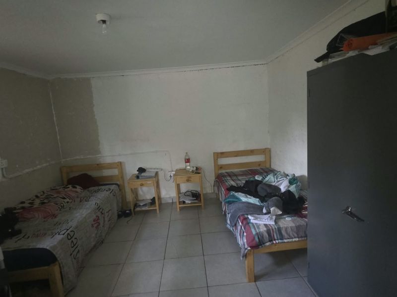 A bedroom featuring tiled flooring and unfinished wall surfaces, requiring cosmetic updates and finishing to improve the overall aesthetic and condition.