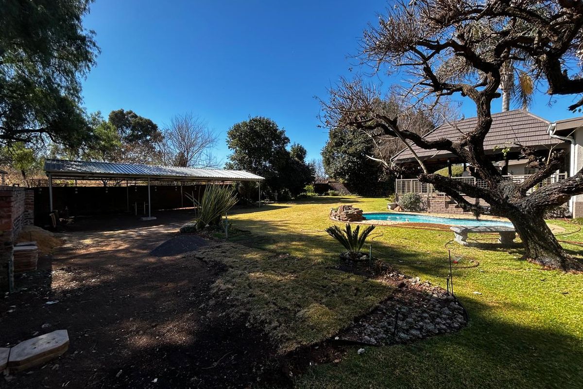 Spacious rear garden featuring a swimming pool, covered patio area, and a large metal carport structure.