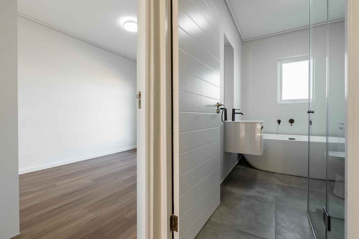 Modern bathroom featuring a sleek freestanding bathtub, wall-mounted vanity, and a glass-enclosed shower, finished with contemporary tiling and clean lines.