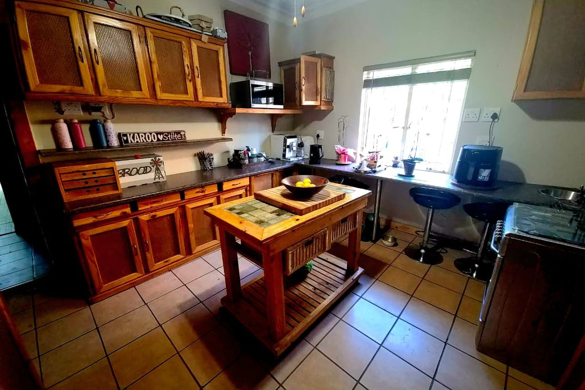 A functional kitchen featuring wooden cabinetry, tiled flooring, and a central island, offering a traditional aesthetic with potential for modern updates.