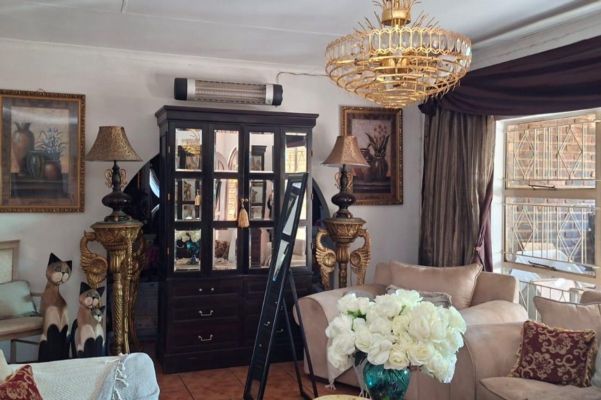 A traditional living room featuring tiled flooring, a large window with security bars, and a decorative ceiling light fixture.