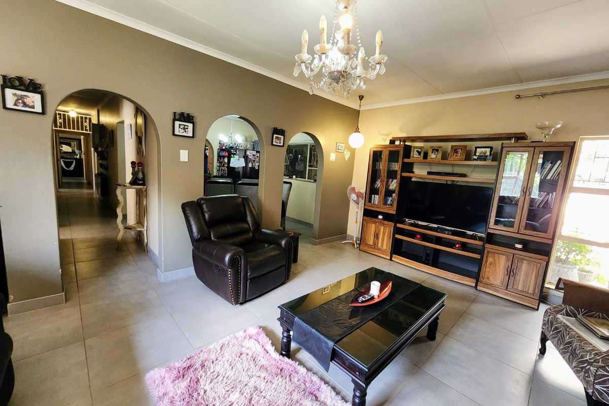 Spacious living room featuring arched doorways, tiled flooring, and a decorative chandelier, providing a warm and inviting atmosphere for family relaxation.