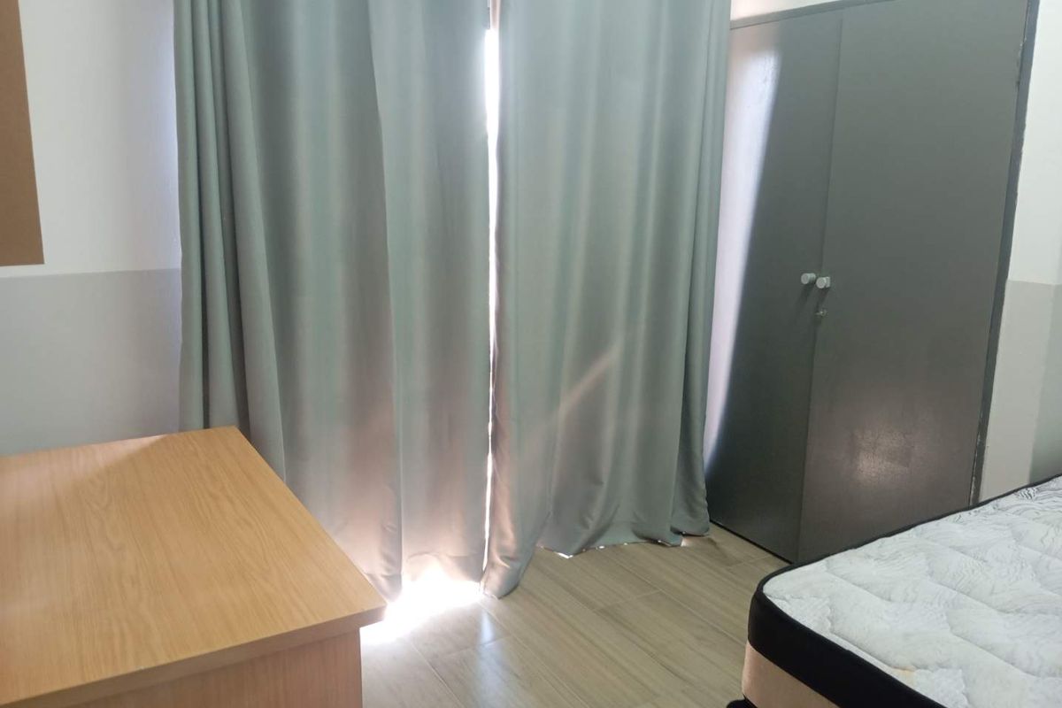 A bedroom featuring laminate flooring and a built-in wardrobe, with natural light entering through the window area.