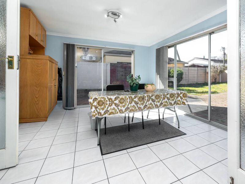Bright dining area featuring tiled flooring, built-in wooden cabinetry, and large sliding glass doors providing direct access to the rear garden.