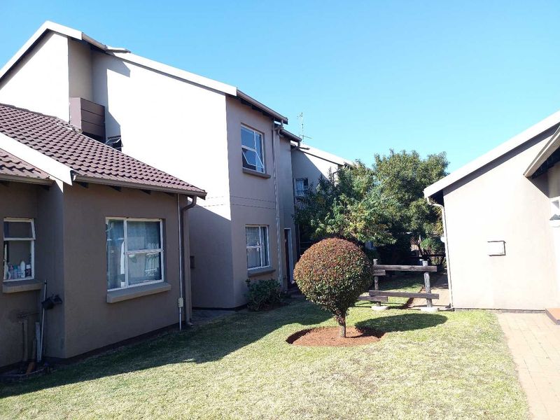 Rear exterior view of the townhouse showing the garden area, paved walkway, and building facade with tiled roofing.