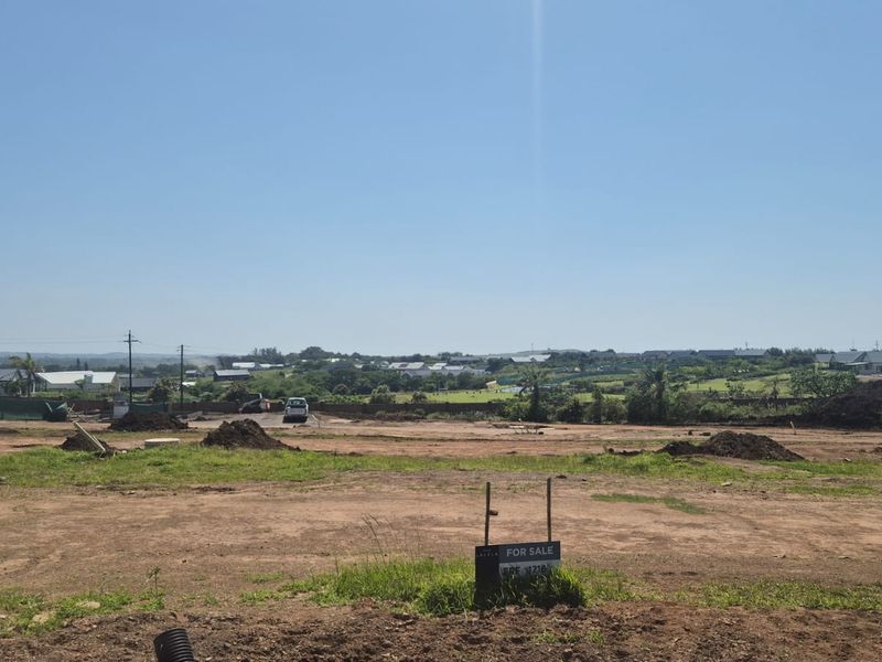 A view of a vacant residential plot of land with earthworks visible, ready for development in a residential estate.