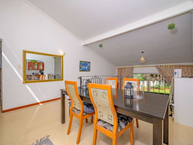 A dining area featuring vaulted ceilings, tiled flooring, and a wrought iron balustrade overlooking the lower level, providing an open and airy atmosphere.