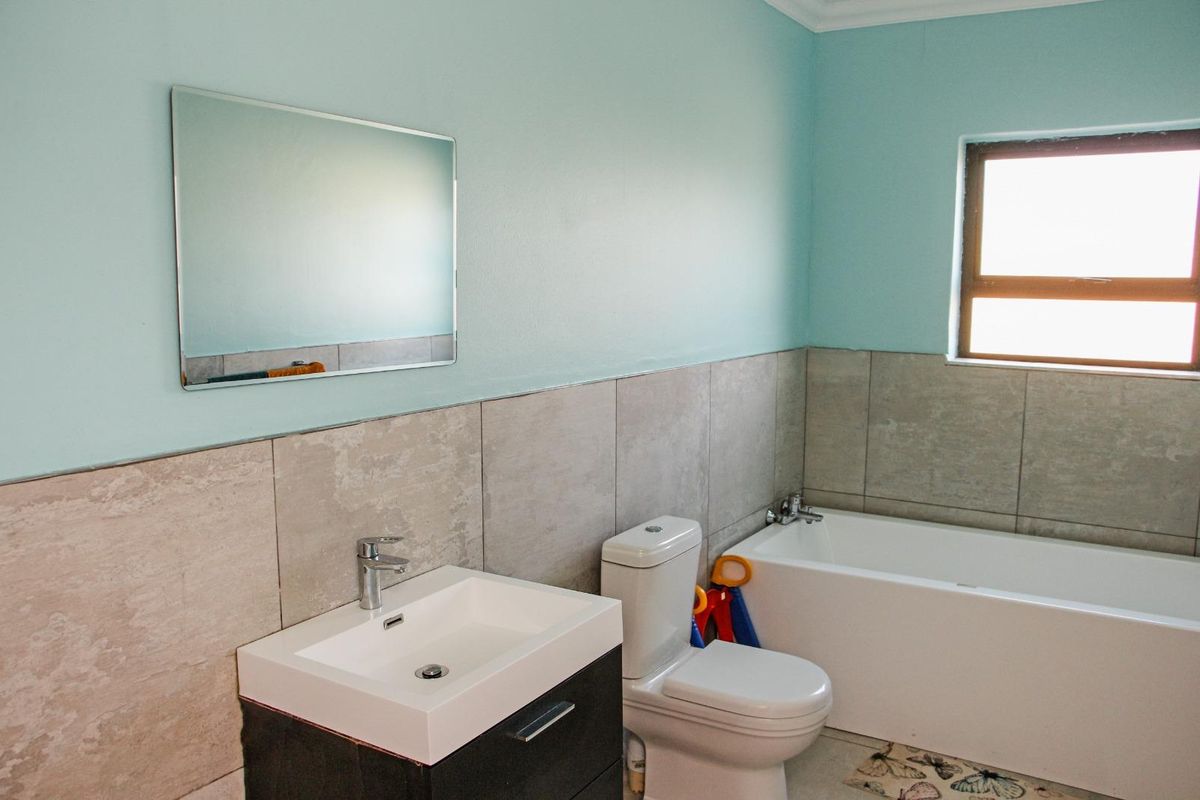A functional bathroom featuring a modern vanity with basin, a standard toilet, and a bathtub with tiled wall finishes.