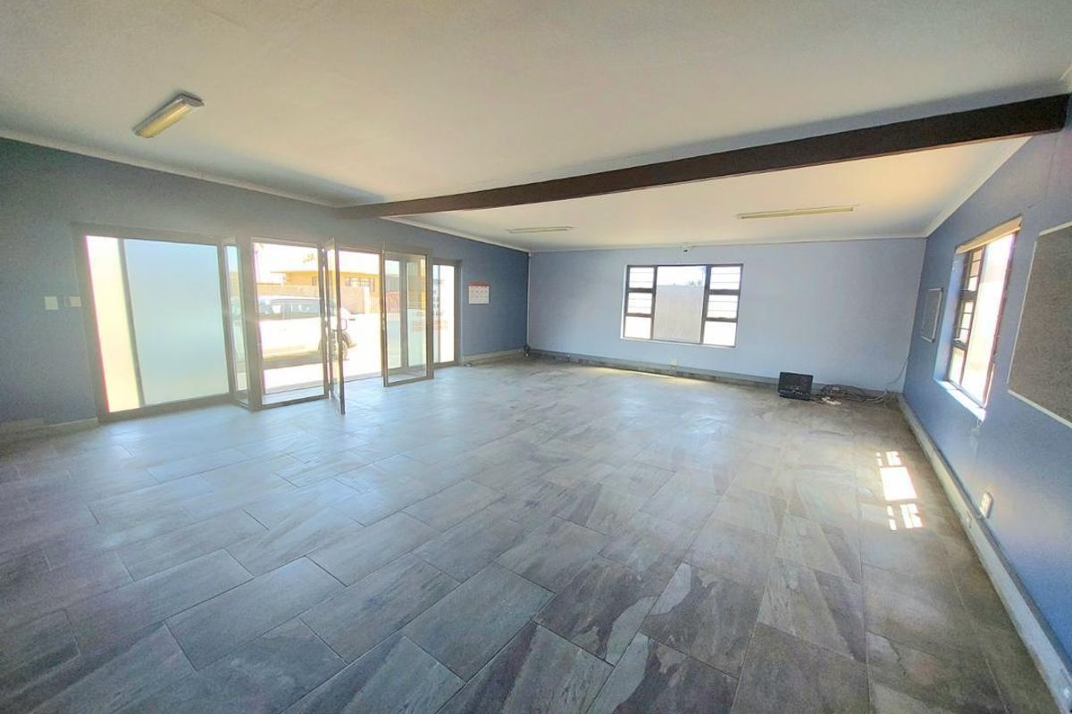 Spacious, open-plan living area featuring large windows, tiled flooring, and sliding glass doors providing ample natural light and direct access to the exterior.