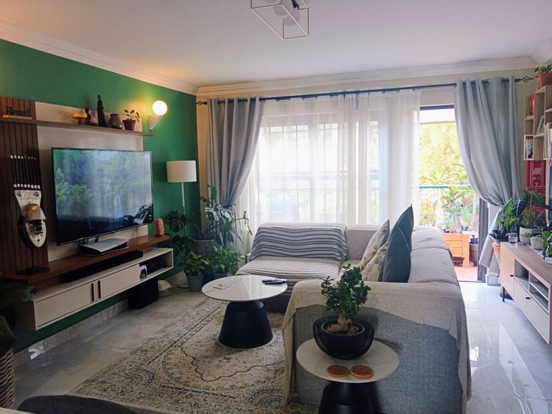 A well-maintained living room featuring a built-in media console, tiled flooring, and direct access to a balcony through sliding glass doors.