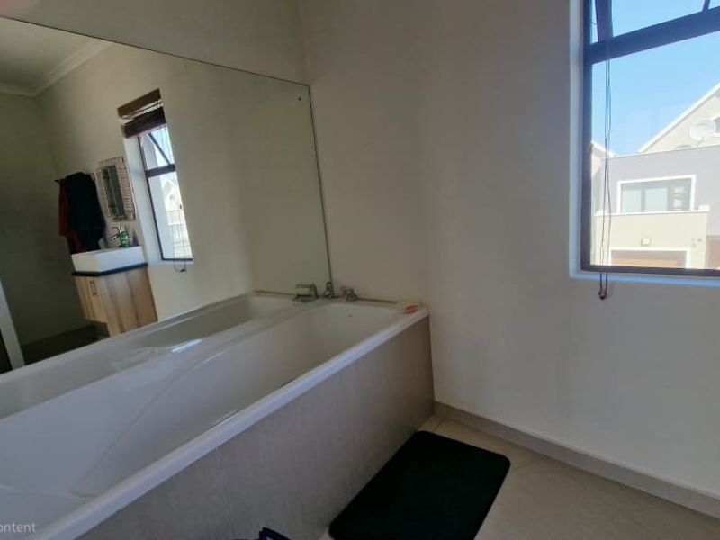 A functional bathroom featuring a built-in bathtub, a large wall mirror, a separate shower enclosure, and a vanity unit with a basin.