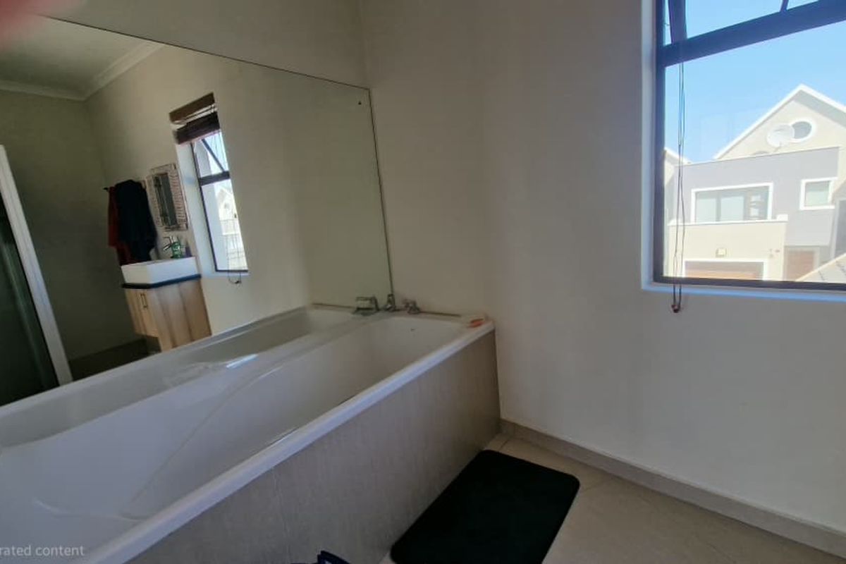 A functional bathroom featuring a built-in bathtub, a large wall mirror, a separate shower enclosure, and a vanity unit with a basin.