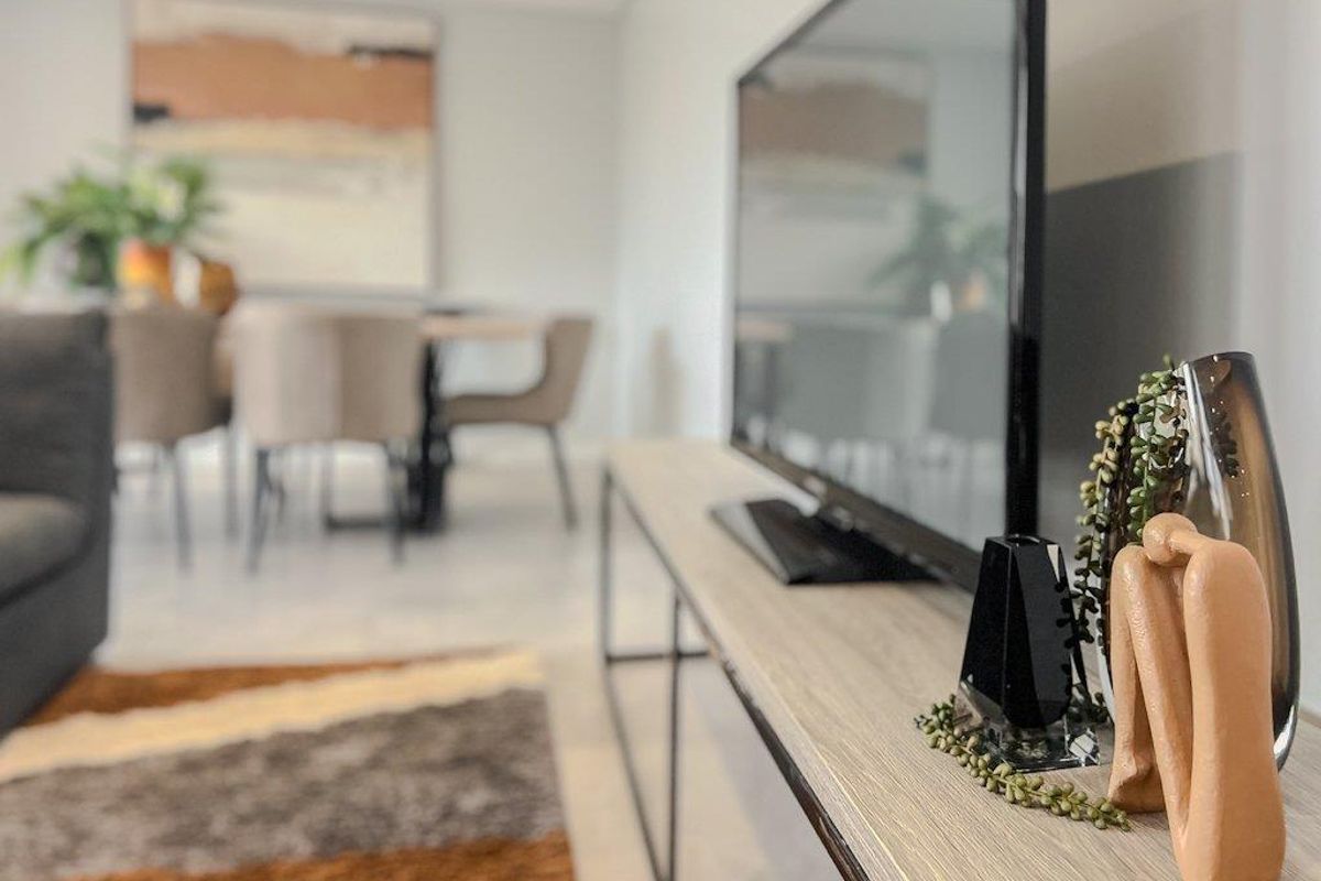A view of a modern living area featuring neutral tones, clean lines, and an open-plan layout connecting to the dining space.