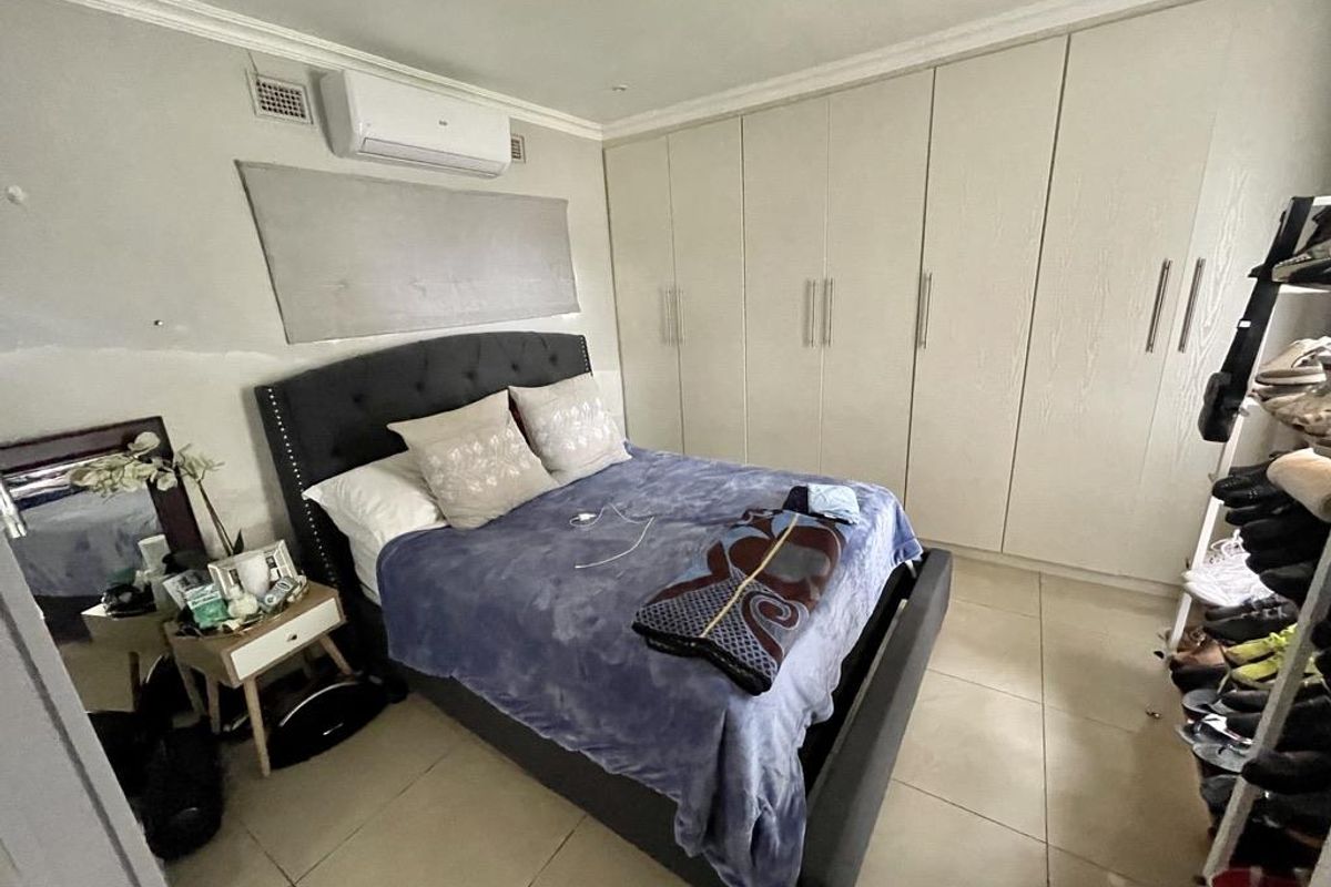 Bedroom featuring tiled flooring, extensive built-in cupboards, and a wall-mounted air conditioning unit.