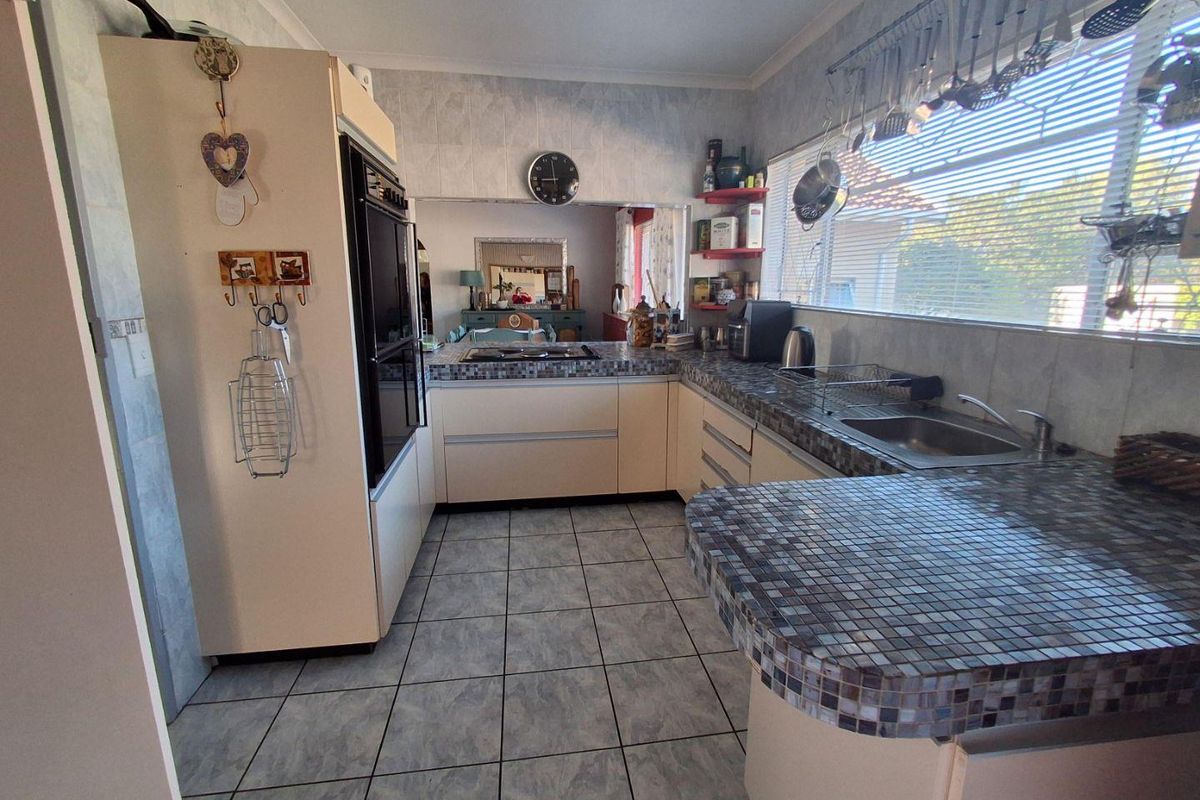 A functional kitchen featuring built-in cabinetry, a double wall oven, a cooktop, and mosaic tile countertops with a breakfast bar extension.