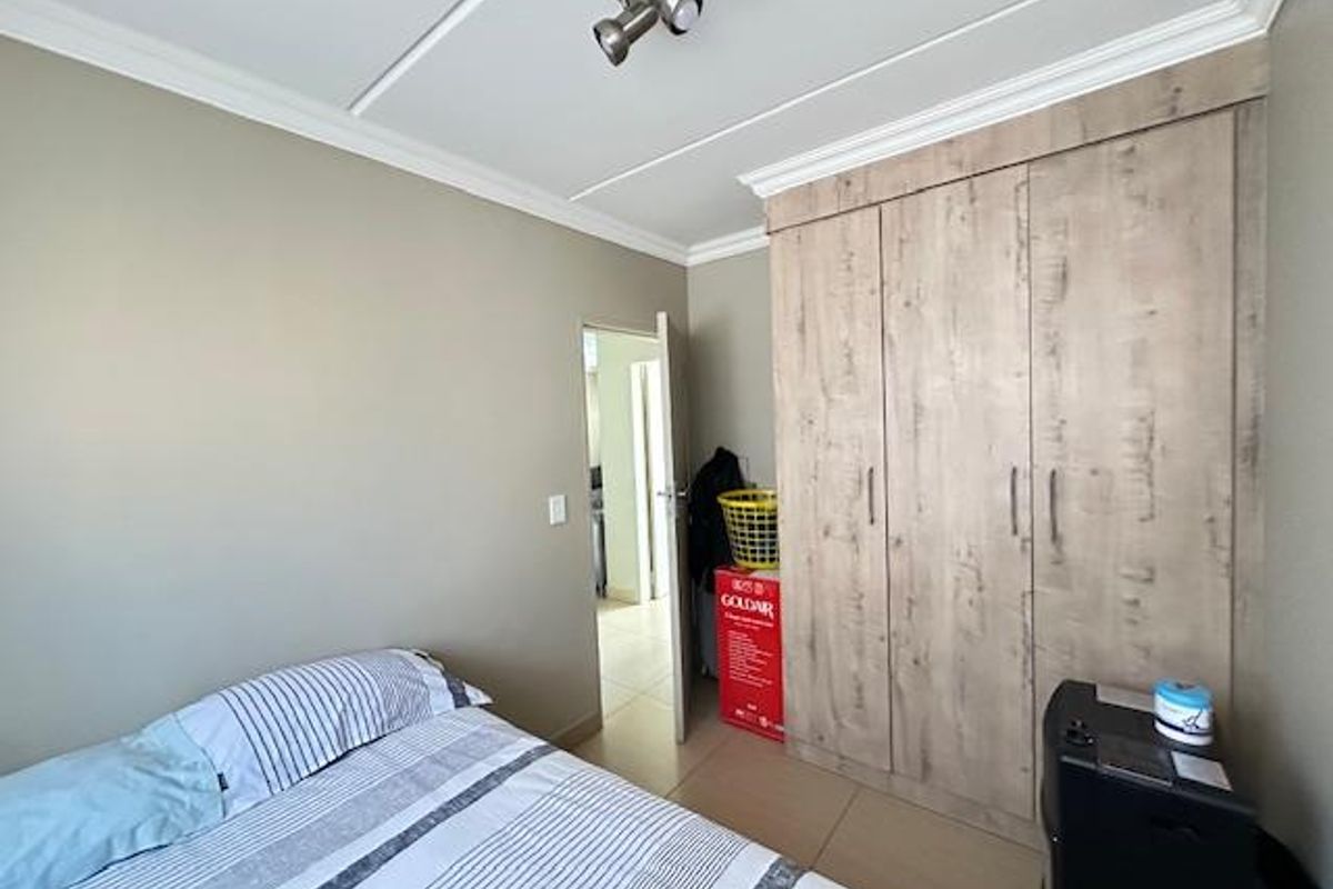 A bedroom featuring built-in wooden cabinetry and tiled flooring, with a doorway leading to an adjacent room.