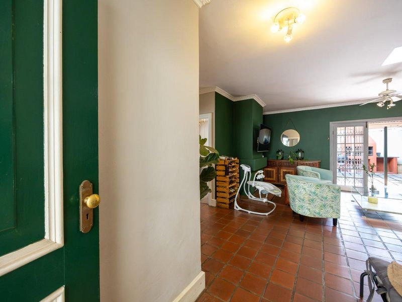 A living room featuring terracotta floor tiles, crown molding, a ceiling fan, and access to an outdoor patio through glass-paned french doors.