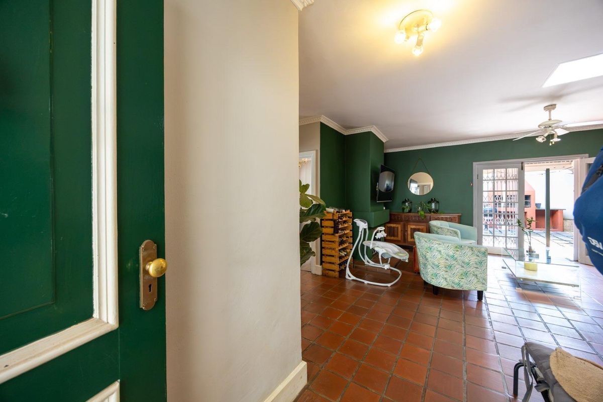 A living room featuring terracotta floor tiles, crown molding, a ceiling fan, and access to an outdoor patio through glass-paned french doors.