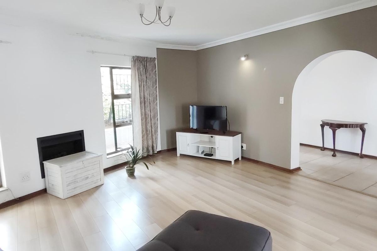 Spacious living room featuring light laminate flooring, a built-in fireplace, and a distinctive arched entryway leading to an adjacent space.