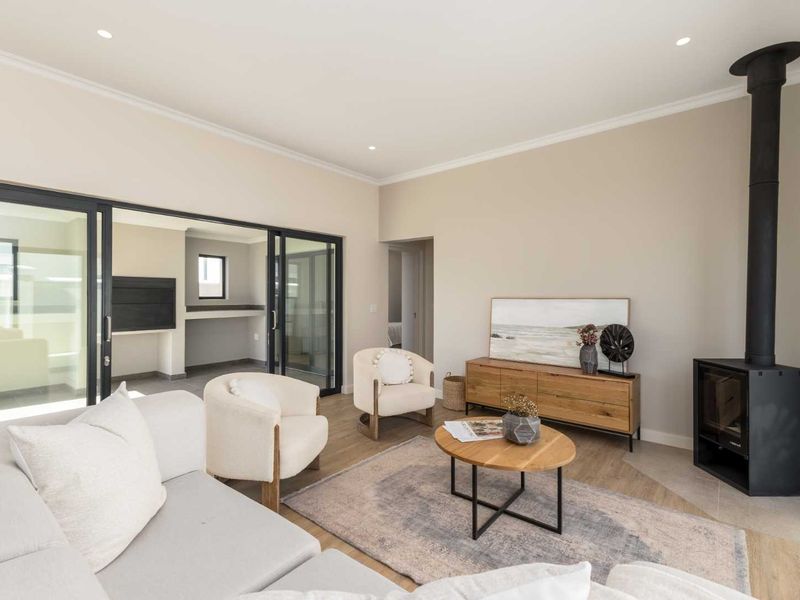 Modern living room featuring a sleek freestanding fireplace, light laminate flooring, and large sliding glass doors that open onto an adjacent patio area.