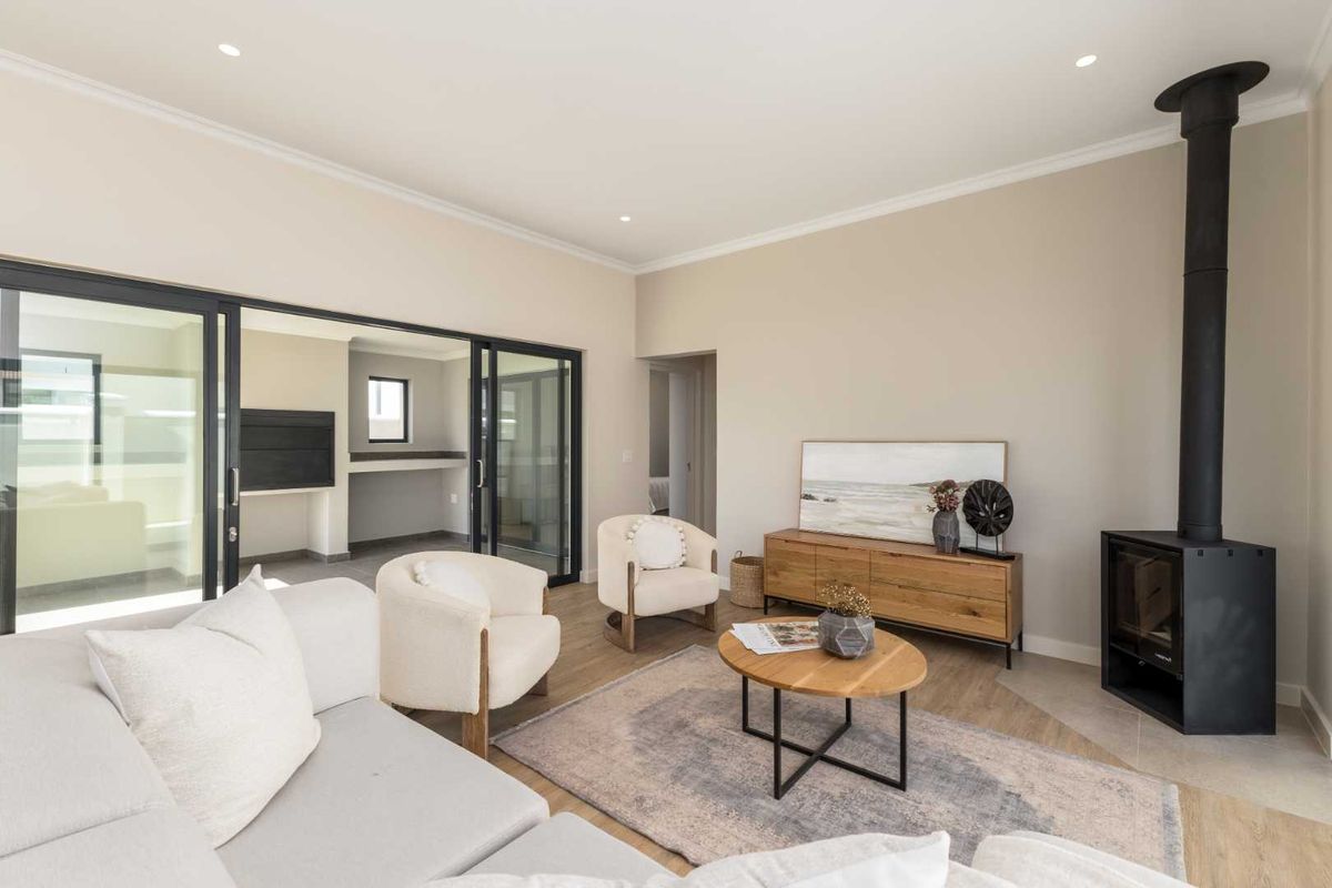 Modern living room featuring a sleek freestanding fireplace, light laminate flooring, and large sliding glass doors that open onto an adjacent patio area.