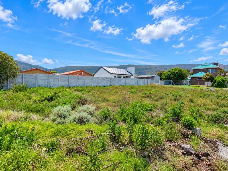 A vacant residential plot of land featuring a precast concrete boundary wall and mountain views in the background.