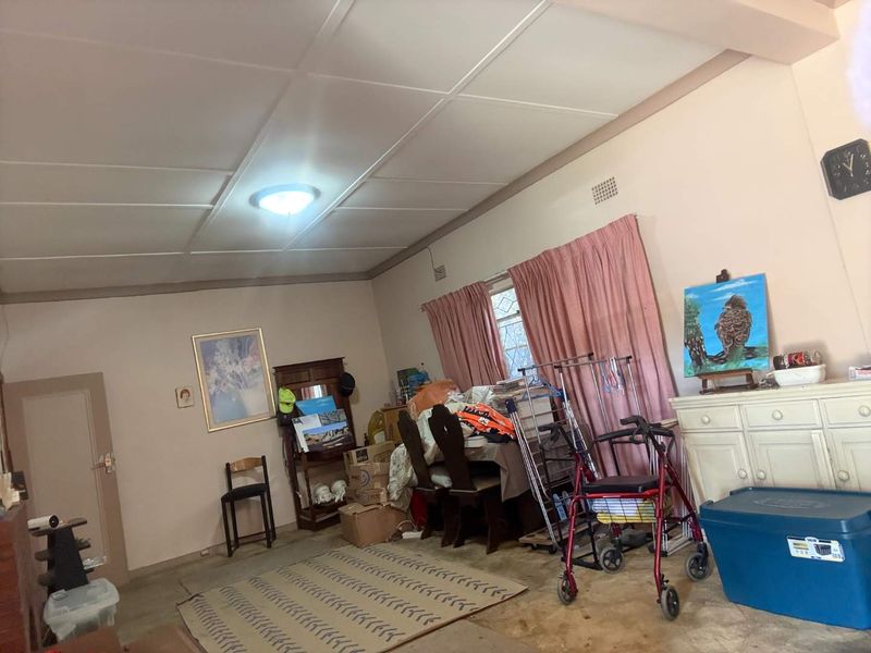 A living room space featuring a tiled ceiling, flush mount lighting, and carpeted flooring, offering a blank canvas for potential renovation and modernization.