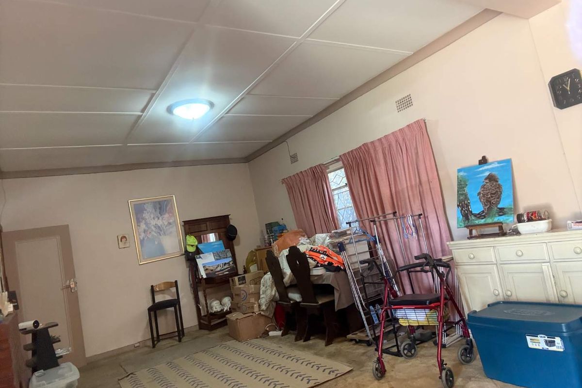 A living room space featuring a tiled ceiling, flush mount lighting, and carpeted flooring, offering a blank canvas for potential renovation and modernization.
