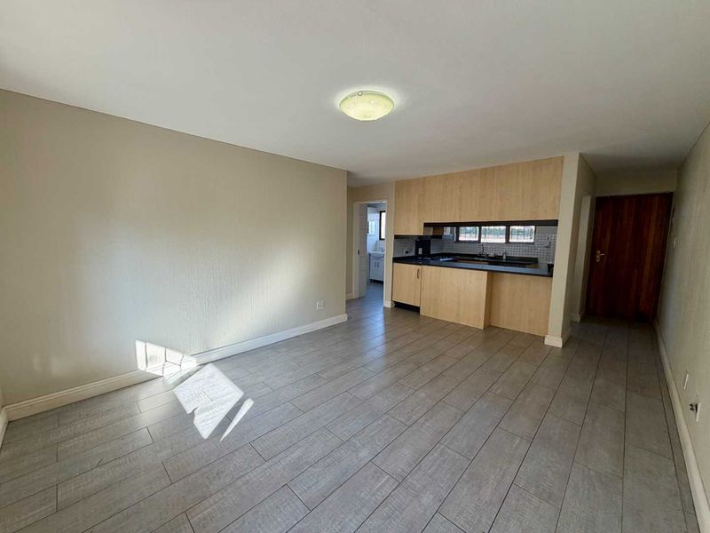 Open plan living area featuring tiled flooring and a functional kitchen with built-in cabinetry, hob, oven, and sink.