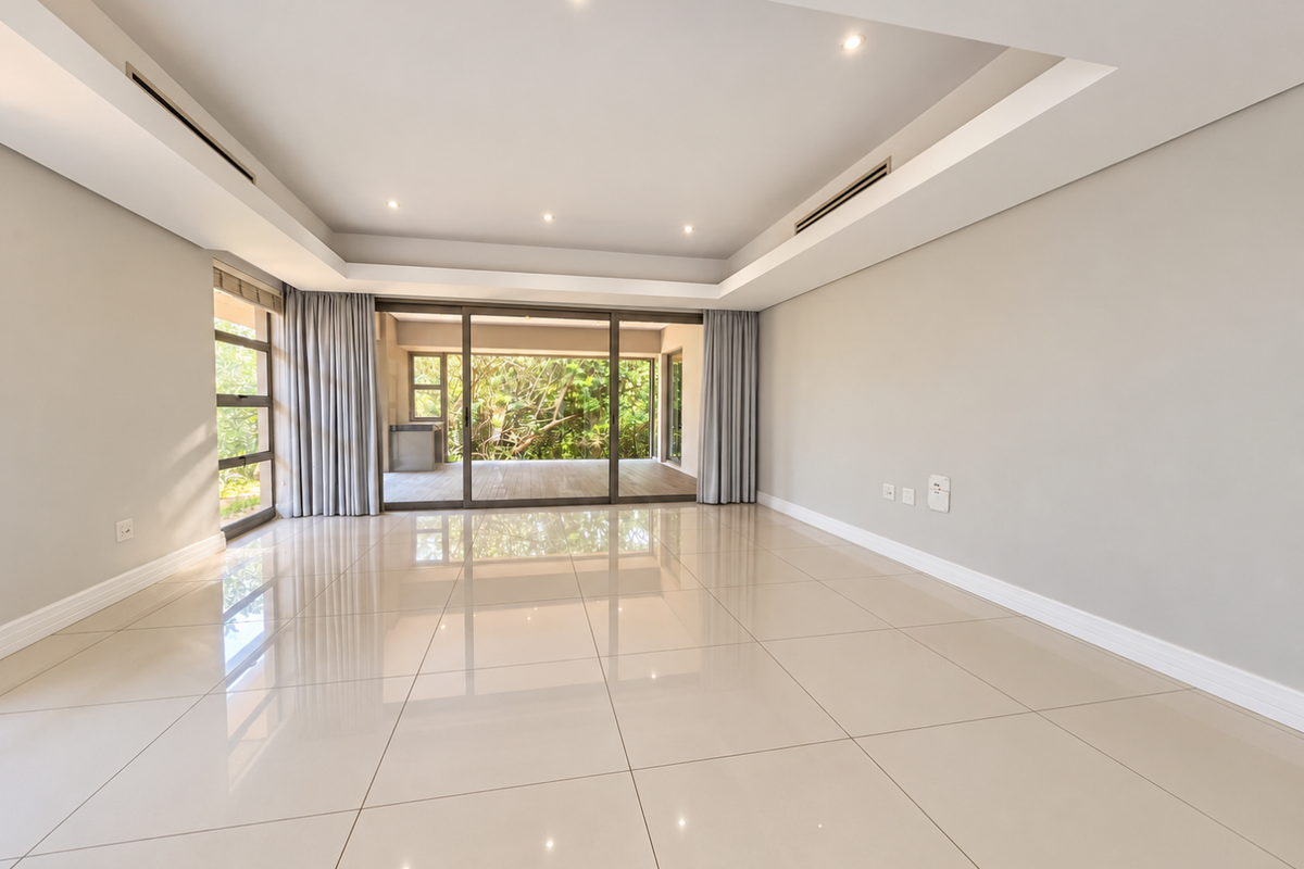 Spacious, light-filled living area featuring polished porcelain tiles, recessed ceiling lighting, ducted air conditioning, and large sliding doors opening to an outdoor patio.