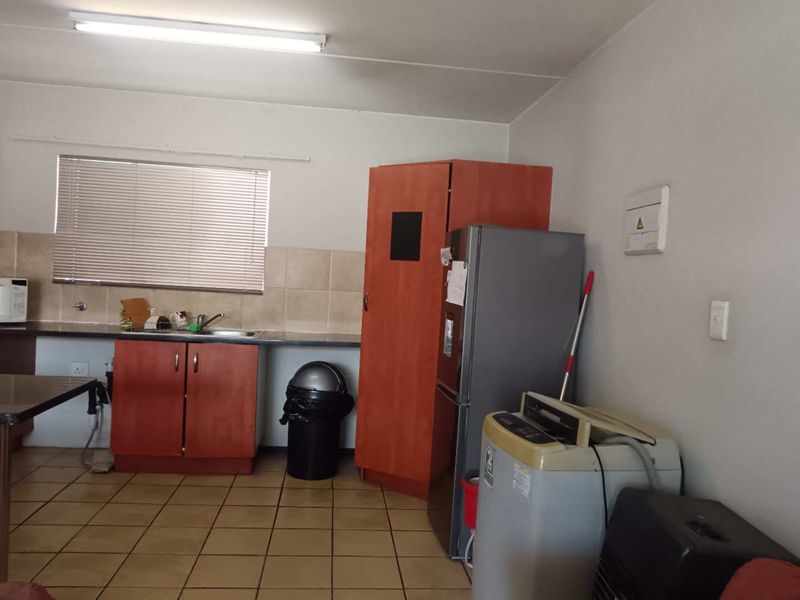 Functional kitchen area featuring built-in cabinetry, laminate countertops, a stainless steel sink, and tiled flooring, offering potential for modernization.