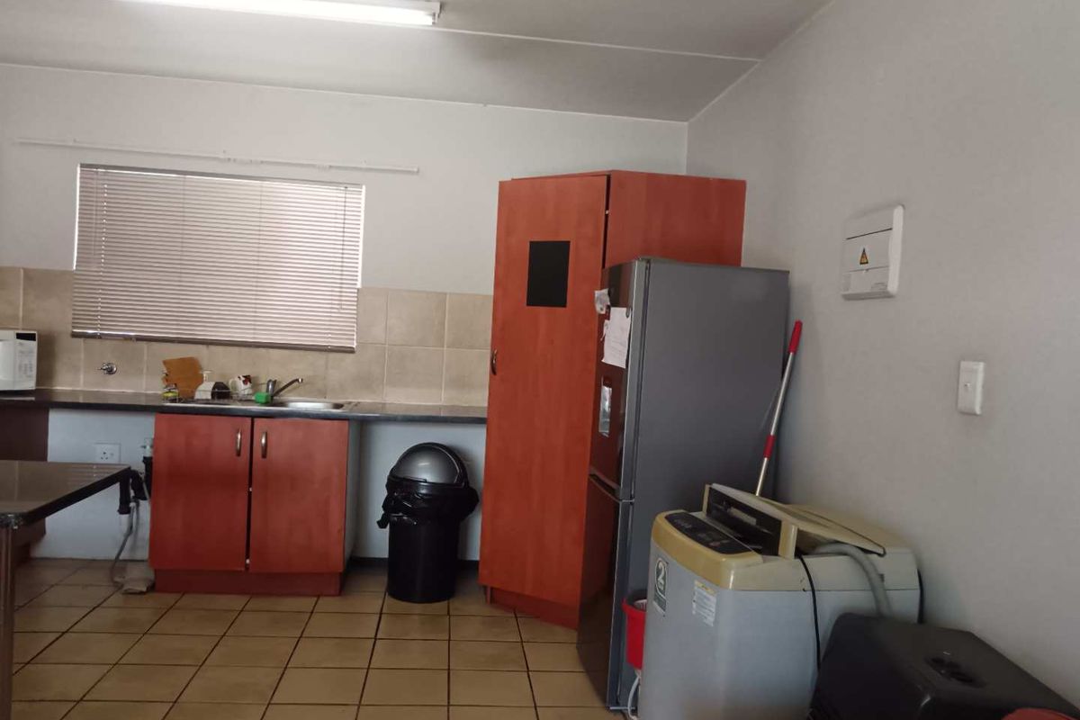 Functional kitchen area featuring built-in cabinetry, laminate countertops, a stainless steel sink, and tiled flooring, offering potential for modernization.