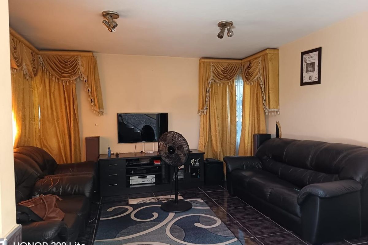 A living room featuring tiled flooring and ceiling-mounted spotlights, providing a functional space for relaxation.