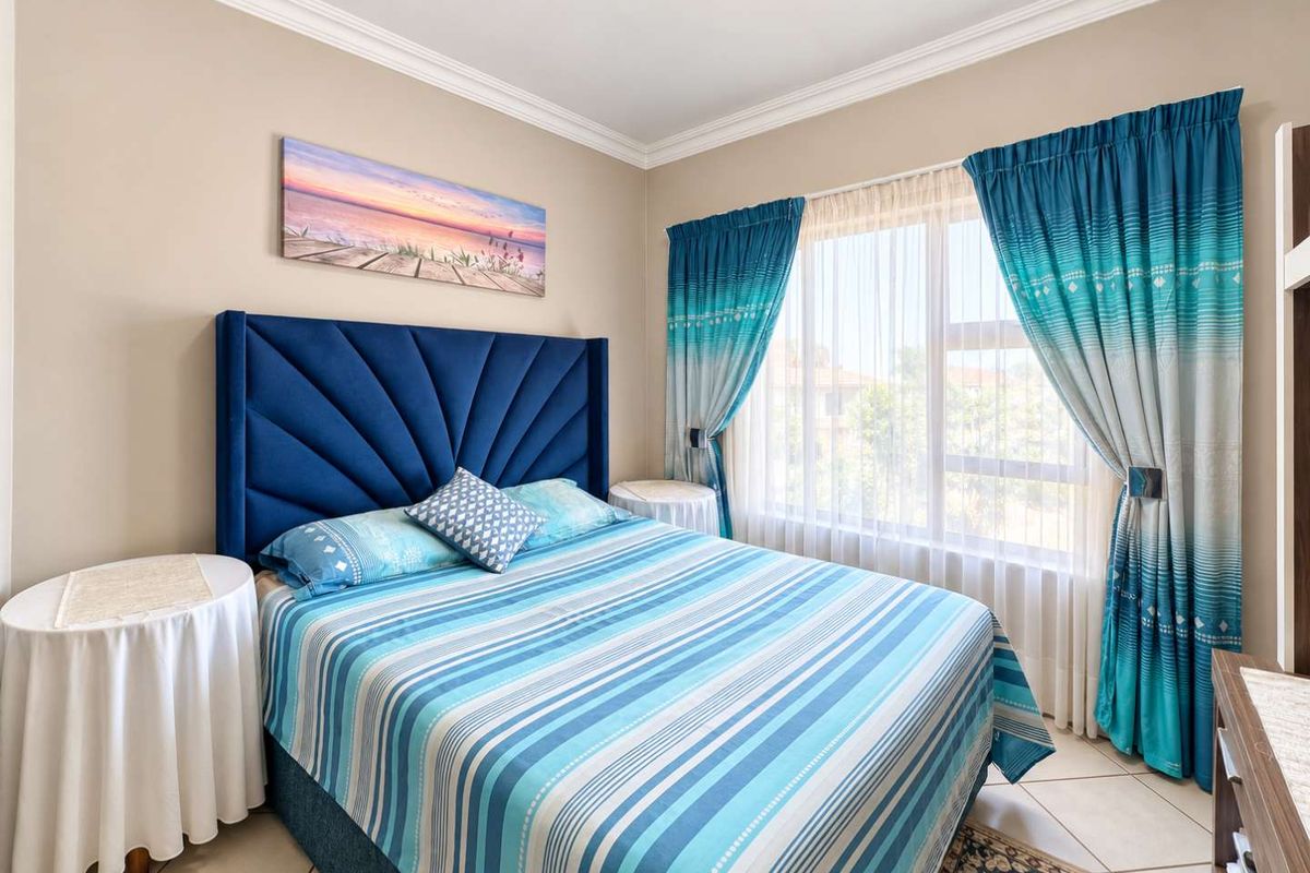 A well-maintained bedroom featuring neutral wall tones, crown molding, and large windows that provide ample natural light.
